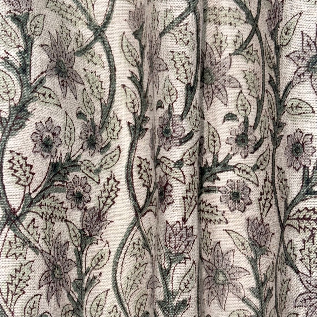 Close-up of floral patterned fabric with green leaves and purple flowers on a grey background