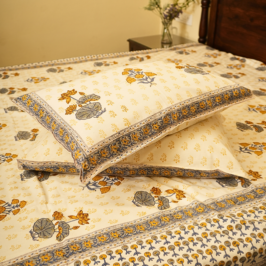 Floral patterned bedspread with matching pillows on a bed.