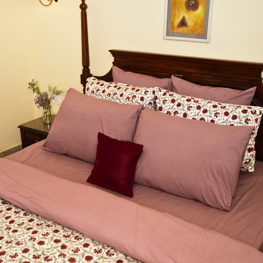 Bed with pink bedding and floral pillows in a bedroom setting.