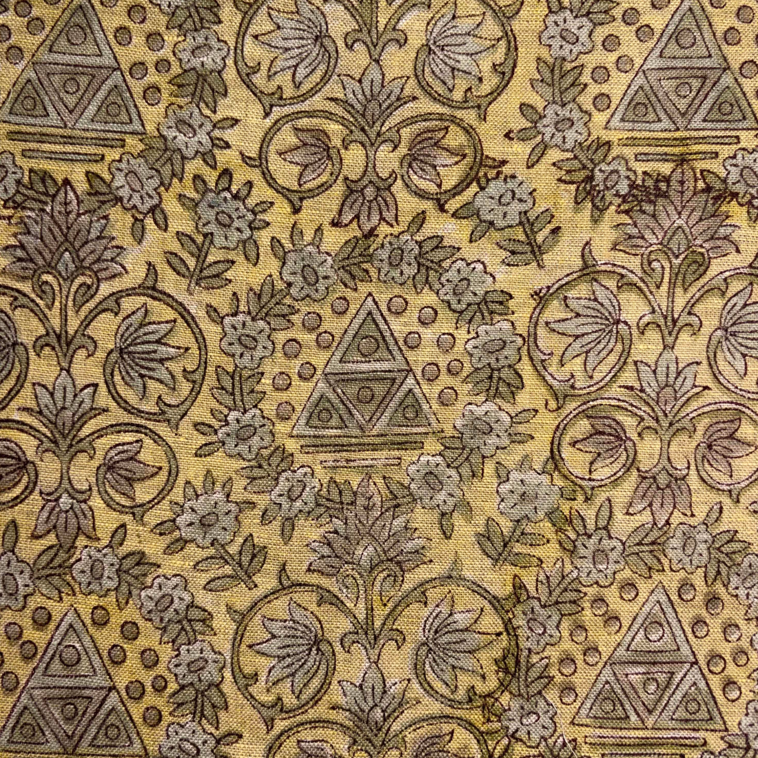 Patterned fabric with geometric and floral designs on a yellow background
