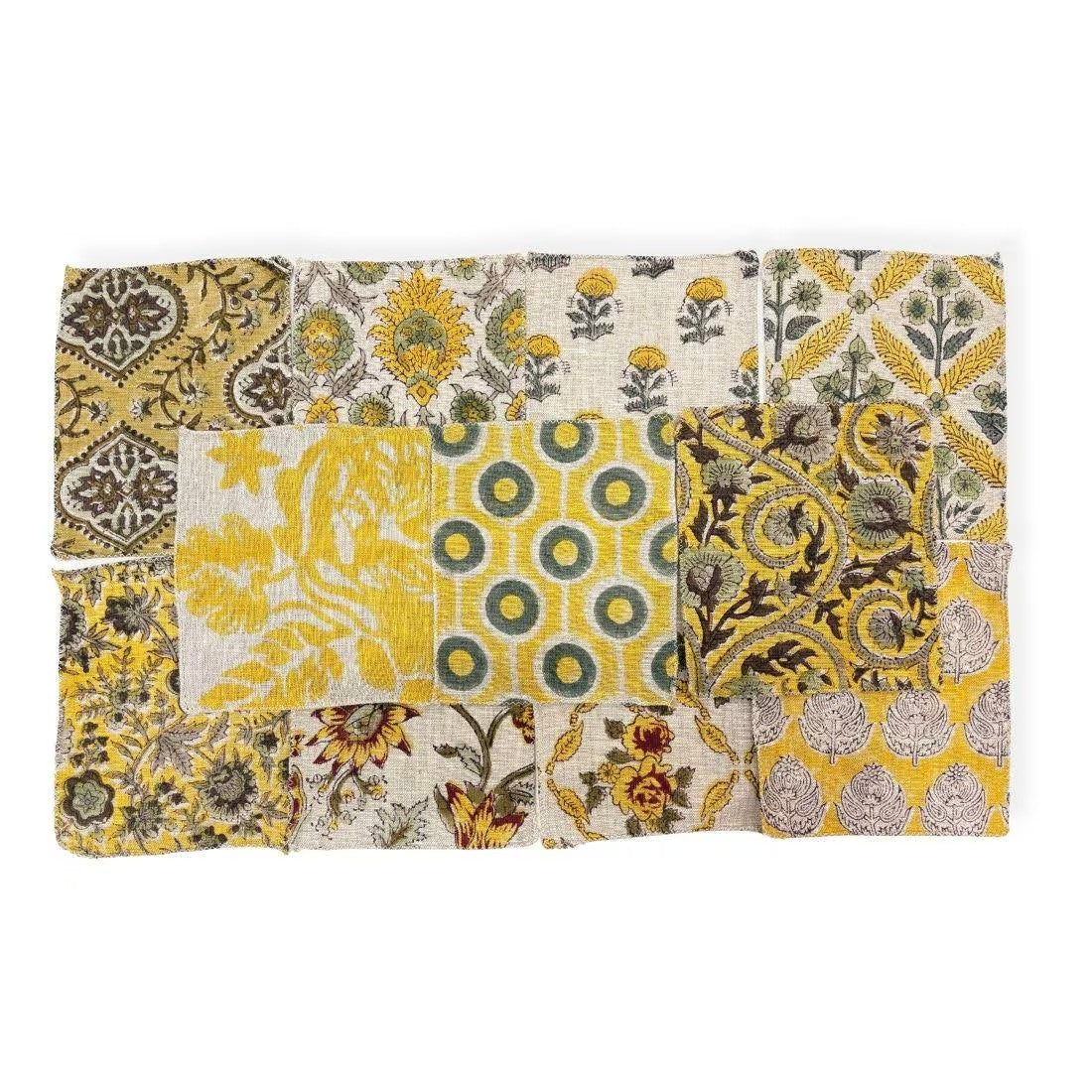 A square patchwork fabric napkin or small table linen featuring a collage of various yellow, green, gray, and brown geometric and floral patterns on a white base.