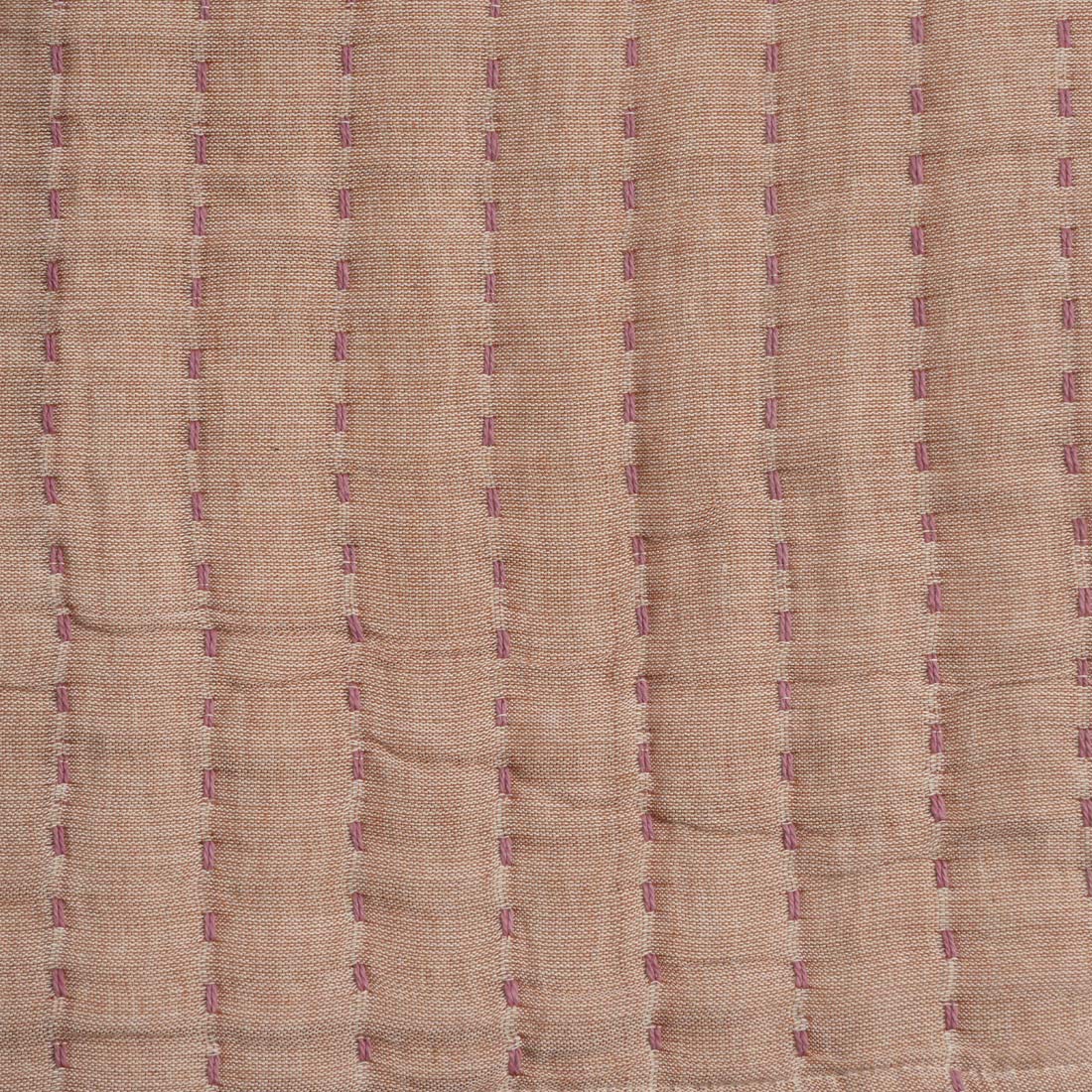 Close-up of beige throw with purple stitching