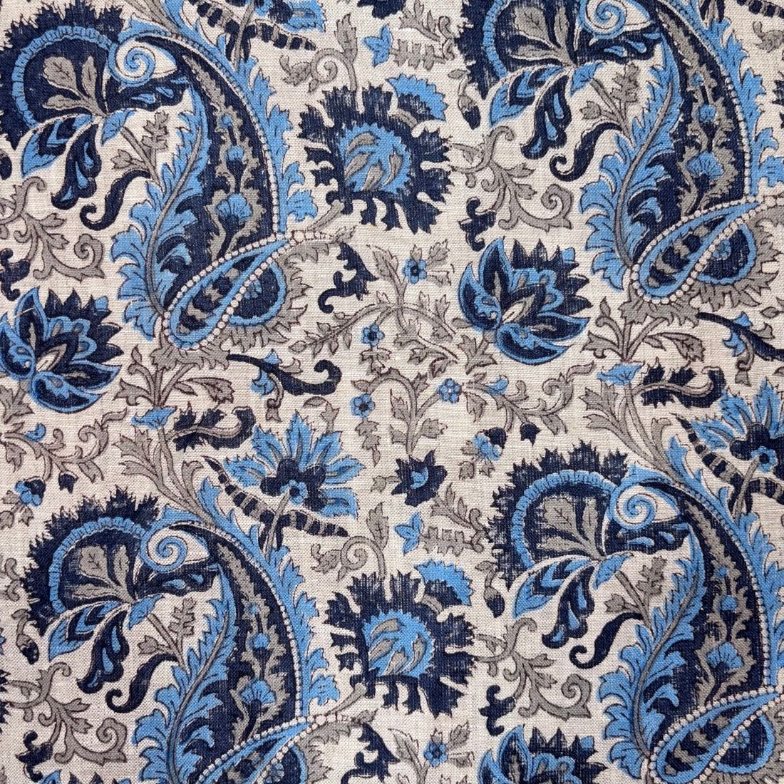 Close-up of a patterned fabric with blue and black paisley design on a grey background