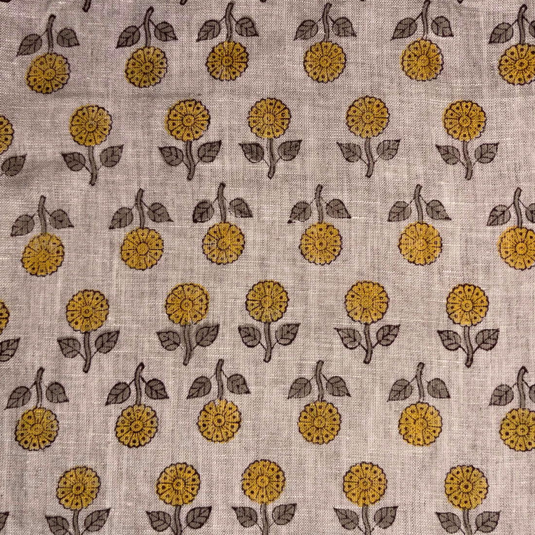 Patterned fabric with yellow flowers and leaves on a beige background