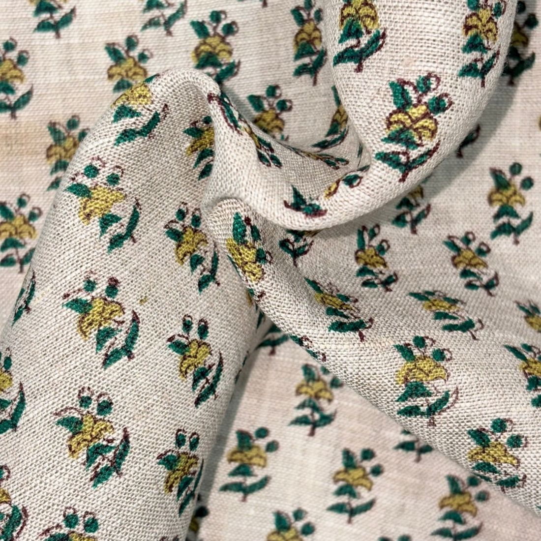 Close-up of floral patterned fabric with green and yellow flowers on a grey background