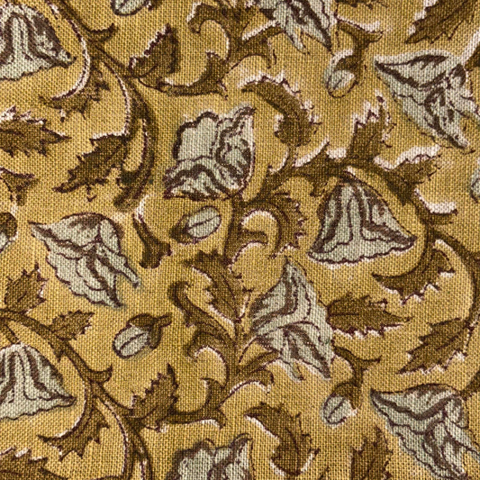 Close-up of a fabric with intricate leaf pattern on a yellow background