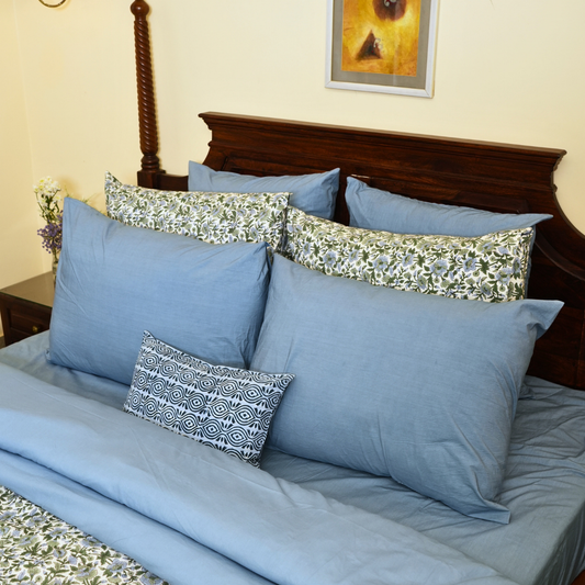 Bed with blue bedding and decorative pillows in a bedroom setting.
