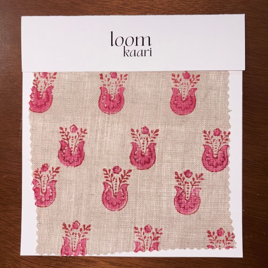Fabric sample with pink floral patterns on beige background, branded 'loom kaari'.