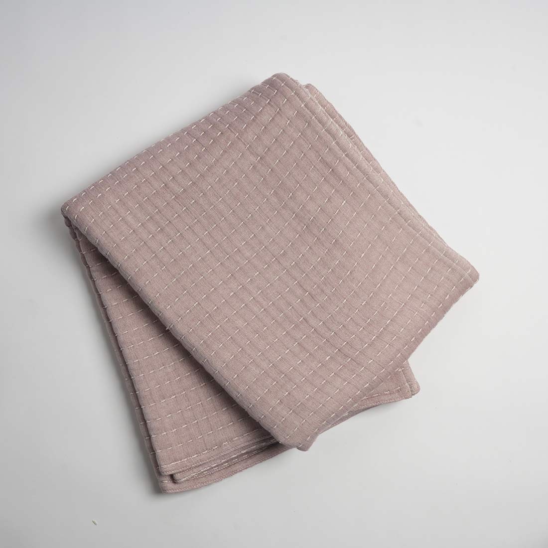 Folded pink textured throw on a light gray background