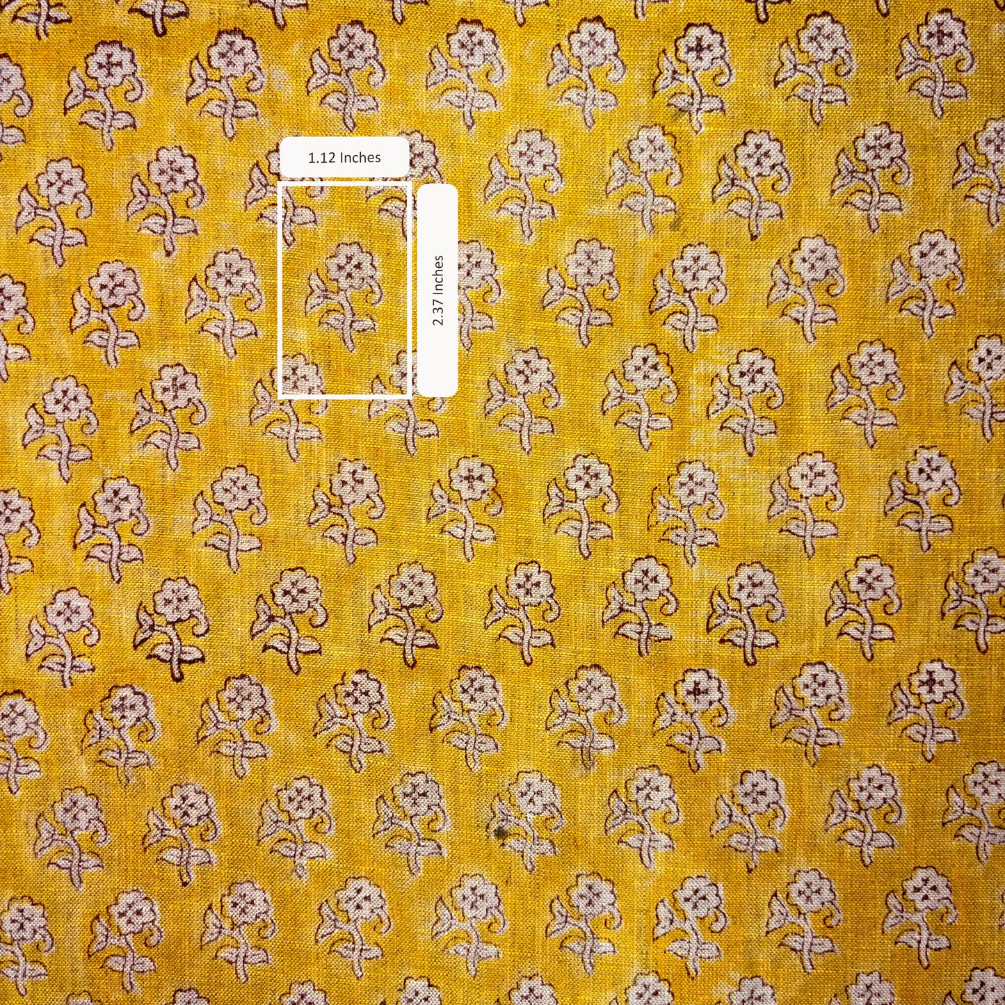 Yellow fabric with small floral pattern and a ruler for scale