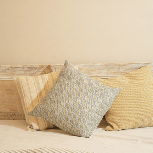 Two pillows on a wooden surface with a neutral background