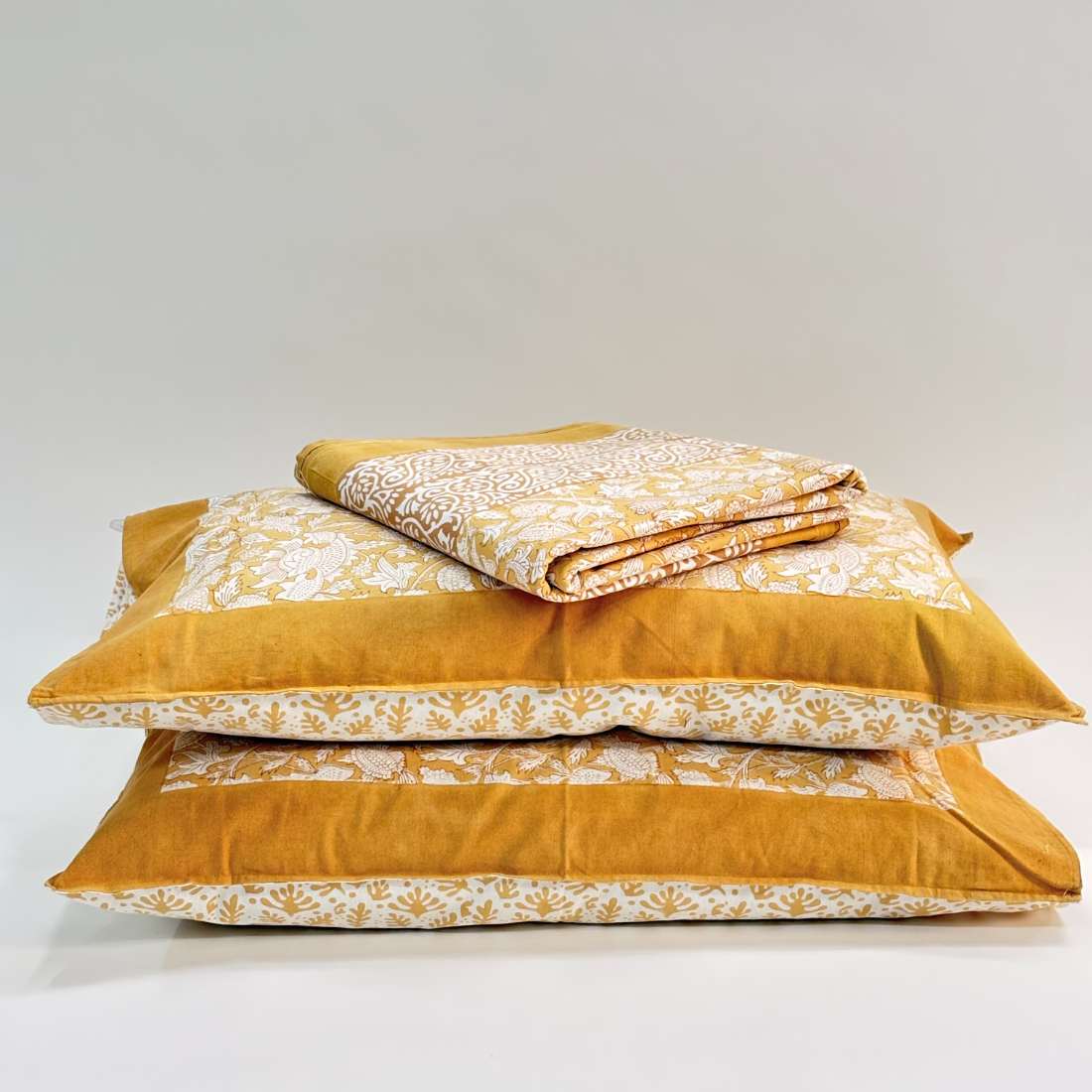 Mustard yellow bedding set with floral patterns on a white background