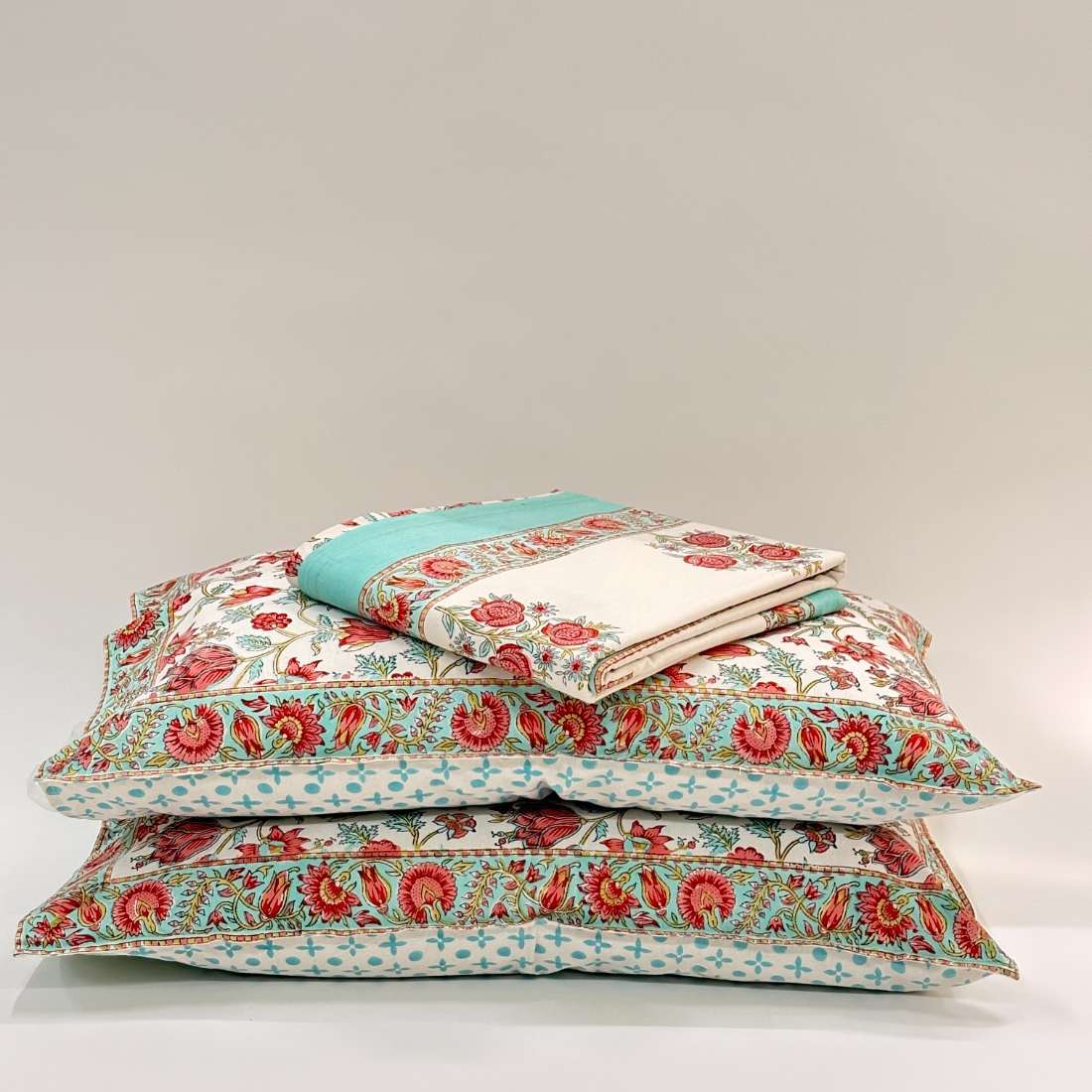Stack of floral-patterned pillows on a light gray background