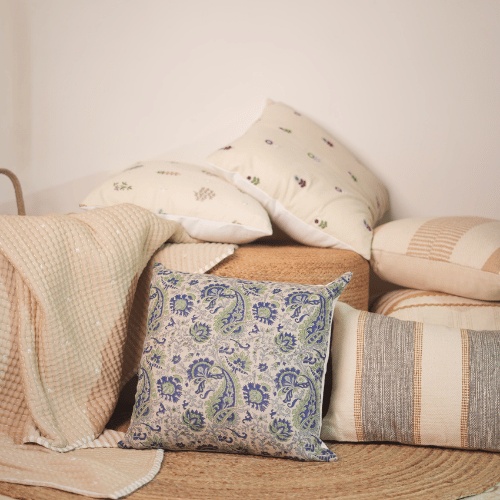Collection of patterned pillows and blankets on a wooden surface with a neutral background