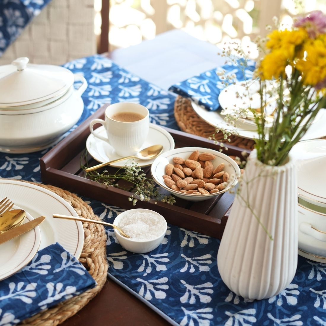Table setting with blue and white patterned tablerunner and napkins.