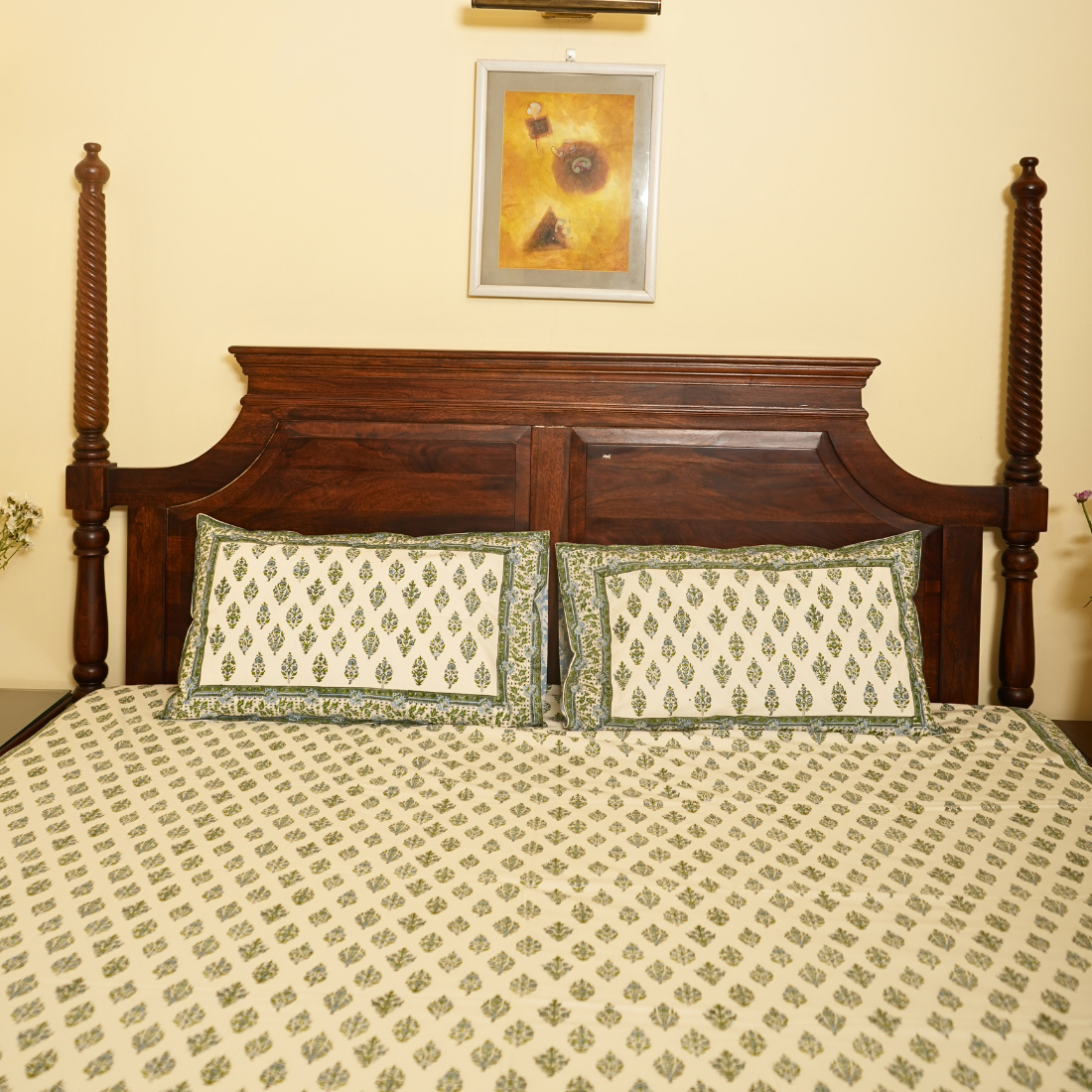 Bed with wooden headboard and patterned bedding, framed picture on wall.