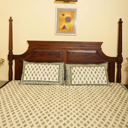 Bed with wooden headboard and patterned bedding, framed picture on wall.