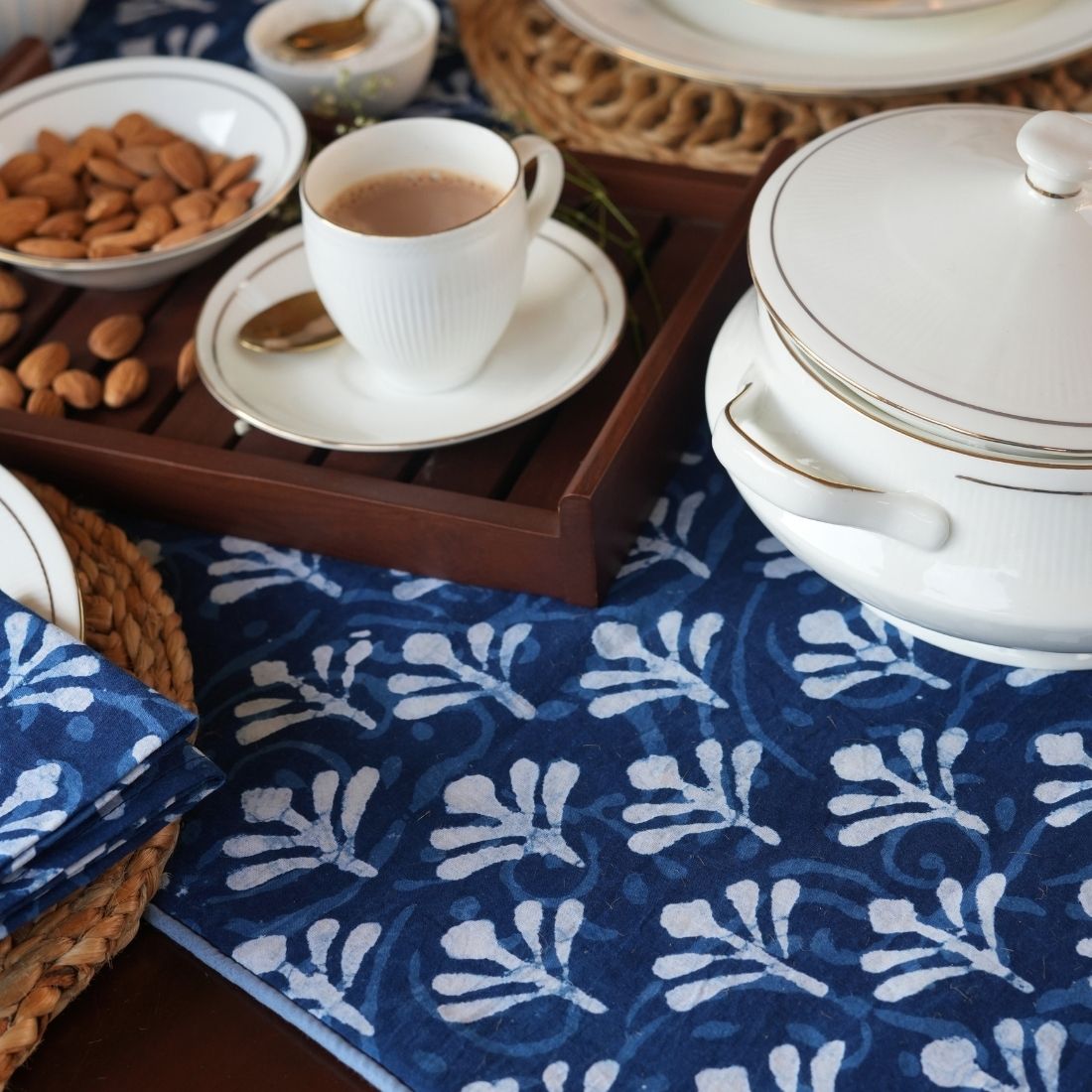 Tea set with a cup, saucer, and cookies on a blue patterned tablerunner.