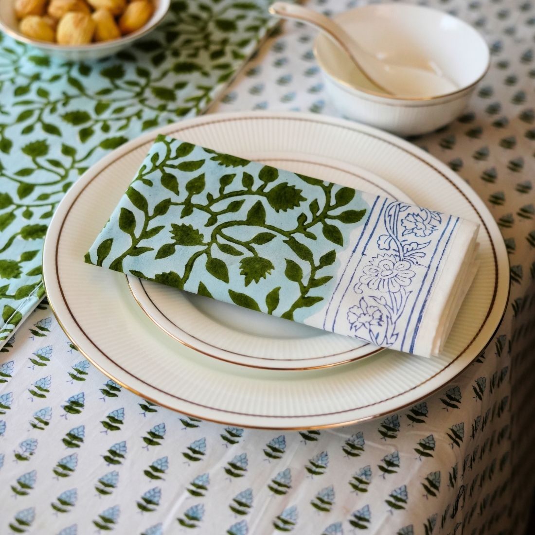 Patterned tablecloth with a plate, bowl, and napkin on a table.