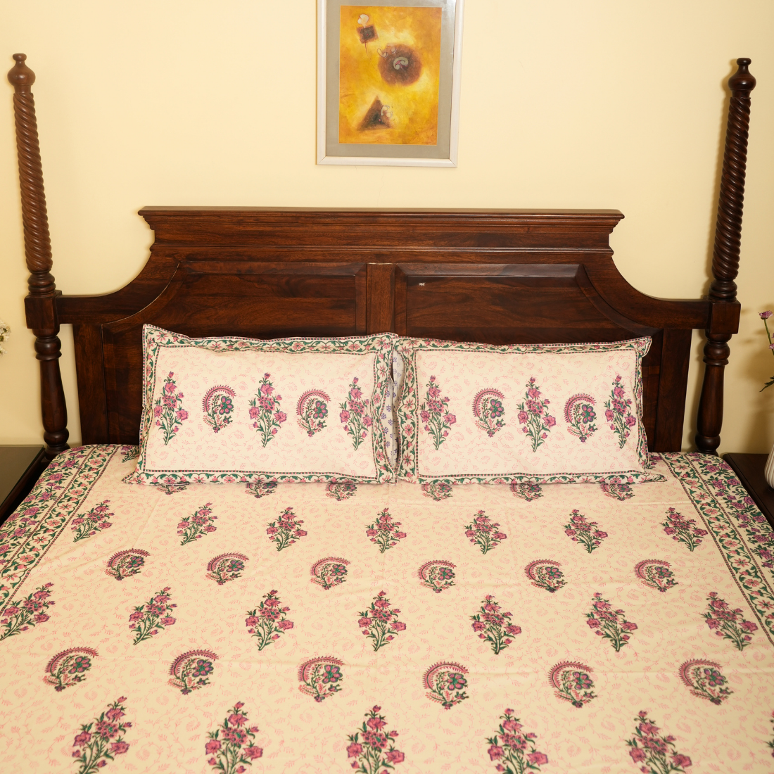 Floral patterned bedspread on a wooden bed with a decorative headboard.