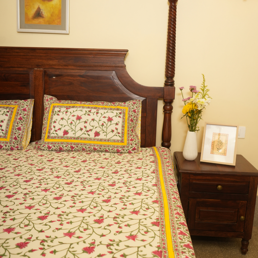 Bedroom with floral bedspread, wooden headboard, and nightstand with decorative items.