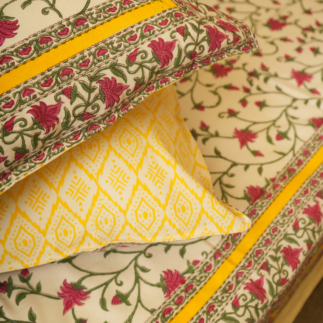 Stack of patterned fabric with floral and geometric designs on a yellow background