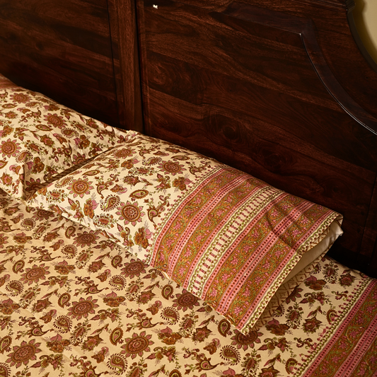 Floral patterned bedspread with decorative pillow on a wooden bed frame.