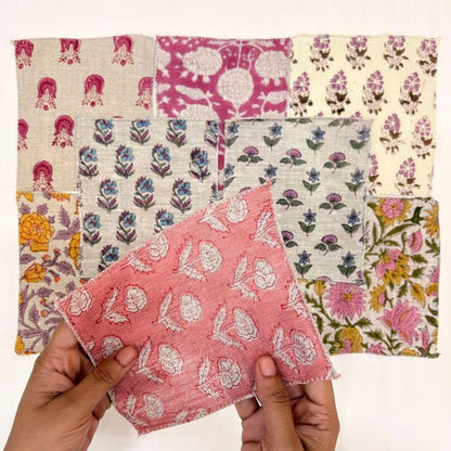 A person's hands hold a pink and white patterned fabric square in front of a grid of nine other colorful patterned fabric squares on a white background.