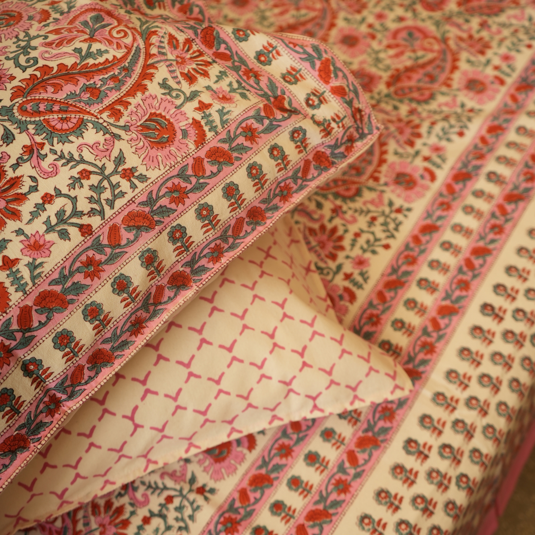 Close-up of patterned fabric with red and green designs on a beige background