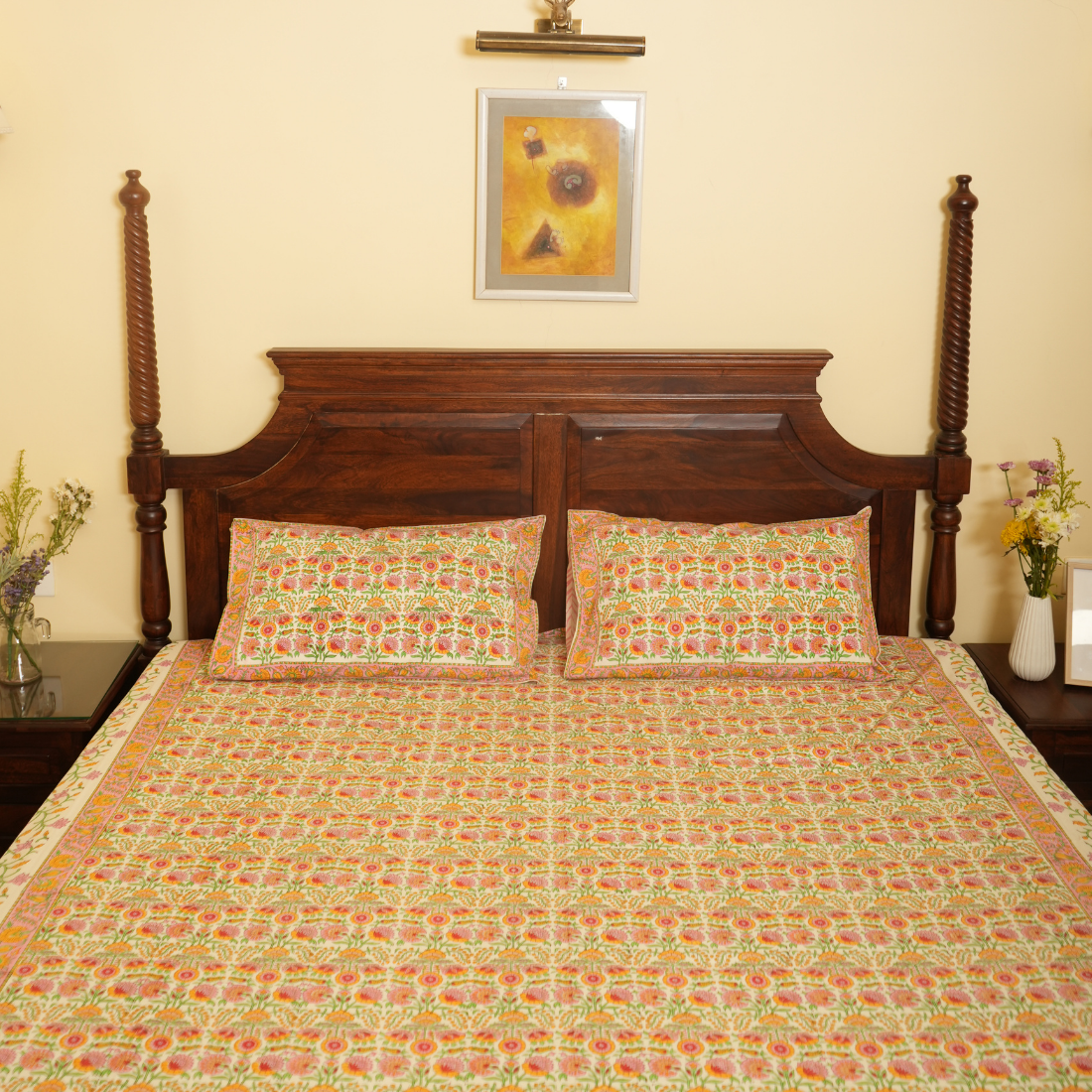 Bed with floral bedding and wooden headboard in a room with a painting on the wall.
