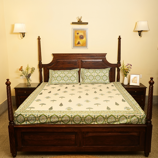 Wooden bed with green and white patterned bedspread in a room with lamps and decor.