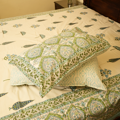 Decorative pillows with green and beige pattern on a matching bedspread.