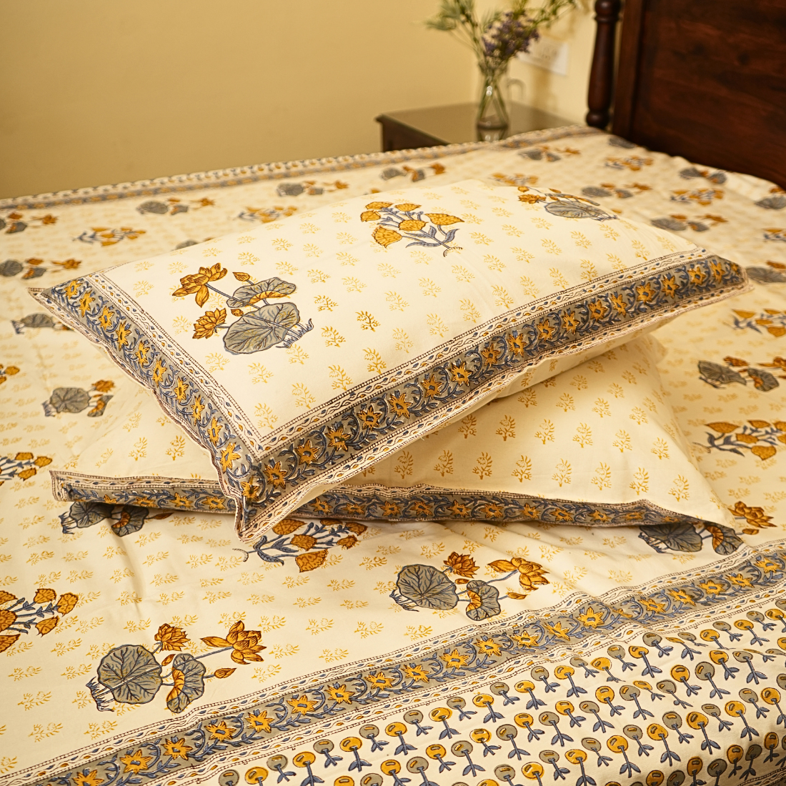 Floral patterned bedspread with matching pillows on a bed.