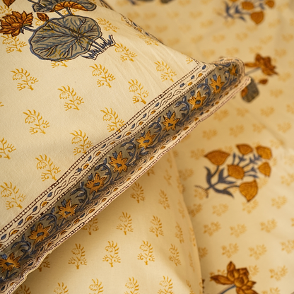 Floral patterned bedsheet with a pillow featuring intricate designs on a beige background.