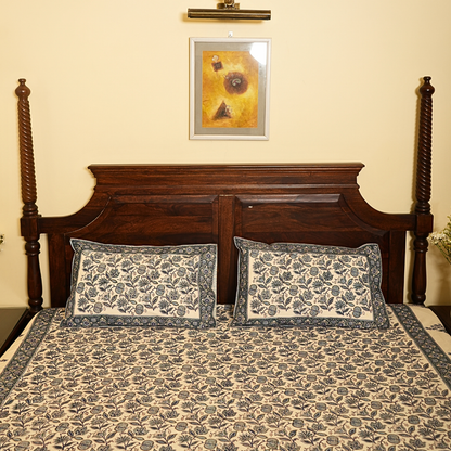 Bed with floral bedding and pillows, wooden headboard, and framed picture on wall.