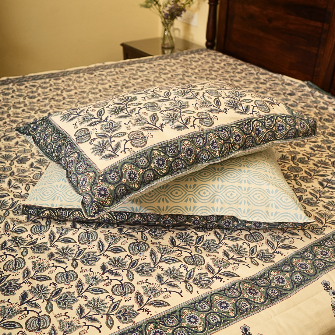 Decorative pillows with floral patterns on a bedspread.
