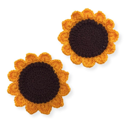 Two sunflower-shaped crochet coasters with brown centers and yellow petals on a white background.