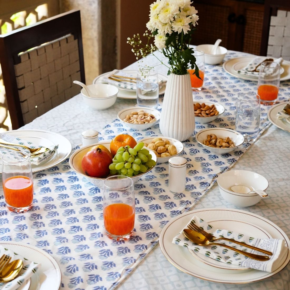 Dining table set with plates, glasses, and food on a patterned tablecloth, table runner and napkins