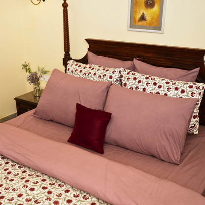 Bed with pink bedding and floral pillows in a bedroom setting.