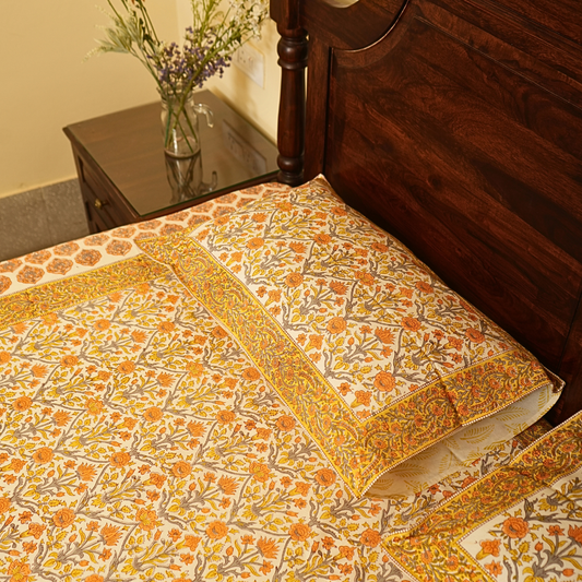 Floral patterned bedspread on a wooden bed with a side table in the background.