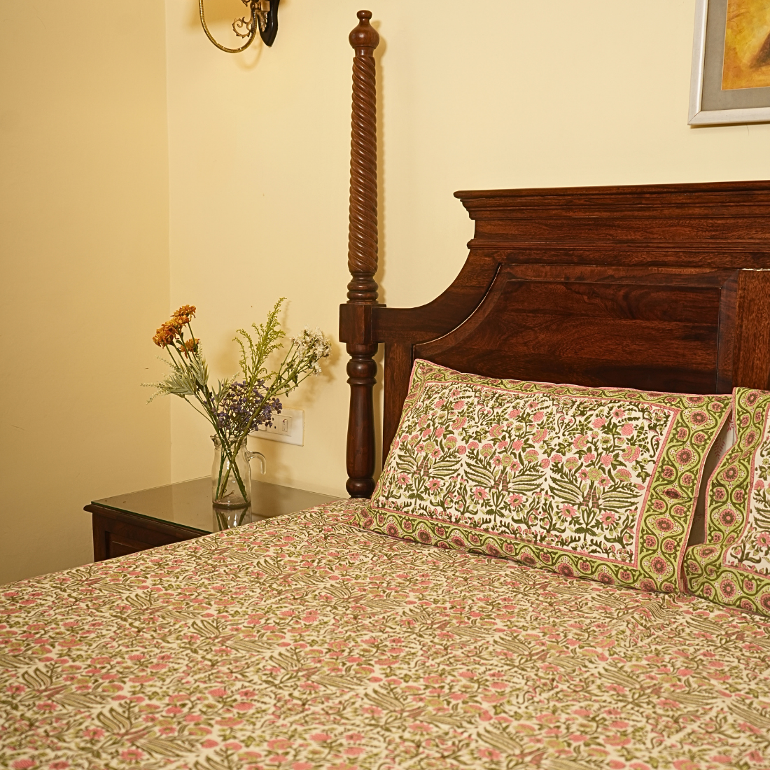 Bed with floral bedding and wooden headboard in a room setting.