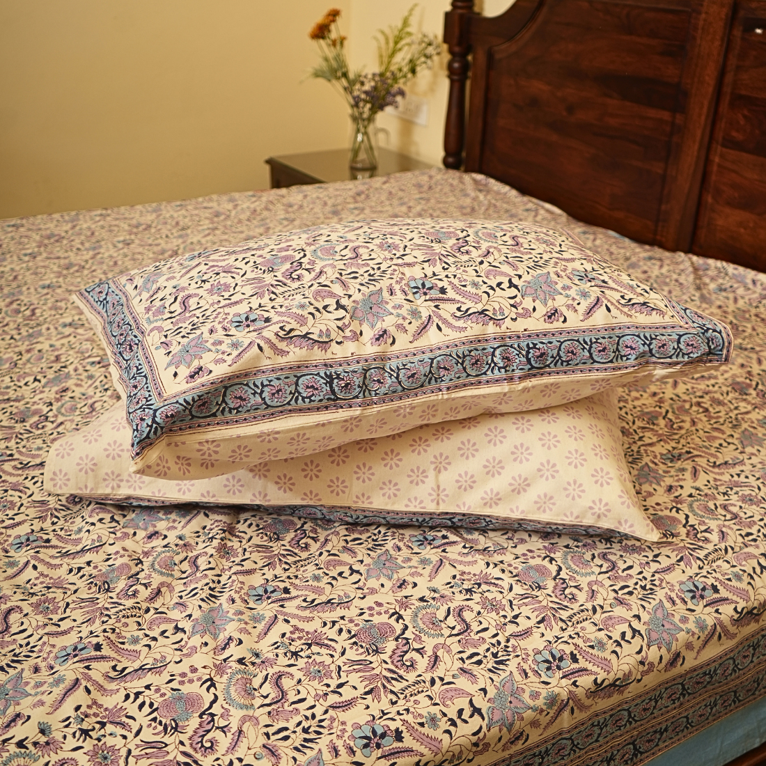 Floral patterned pillows on a bed with a wooden headboard.