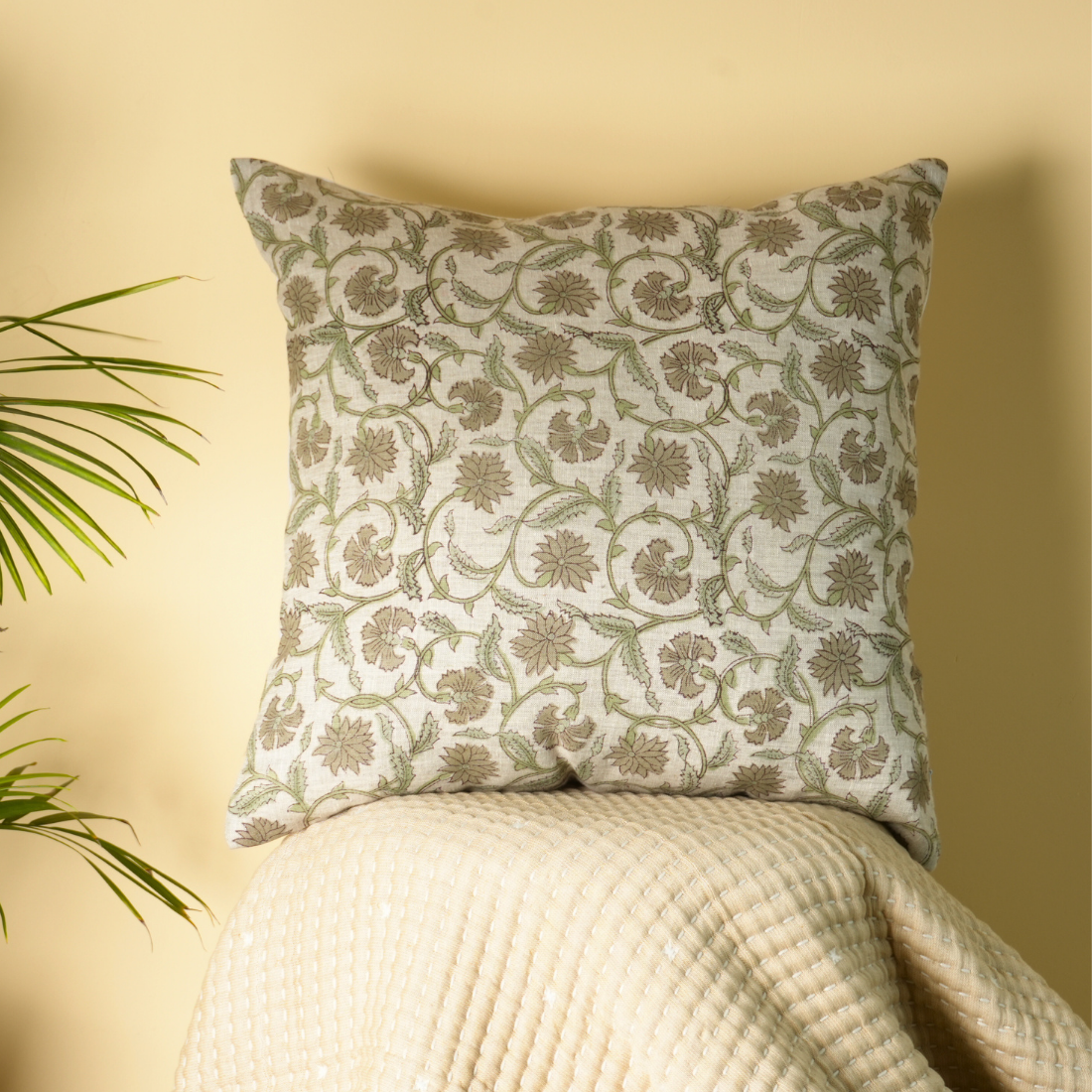 Decorative pillow with floral pattern on a white surface against a yellow wall
