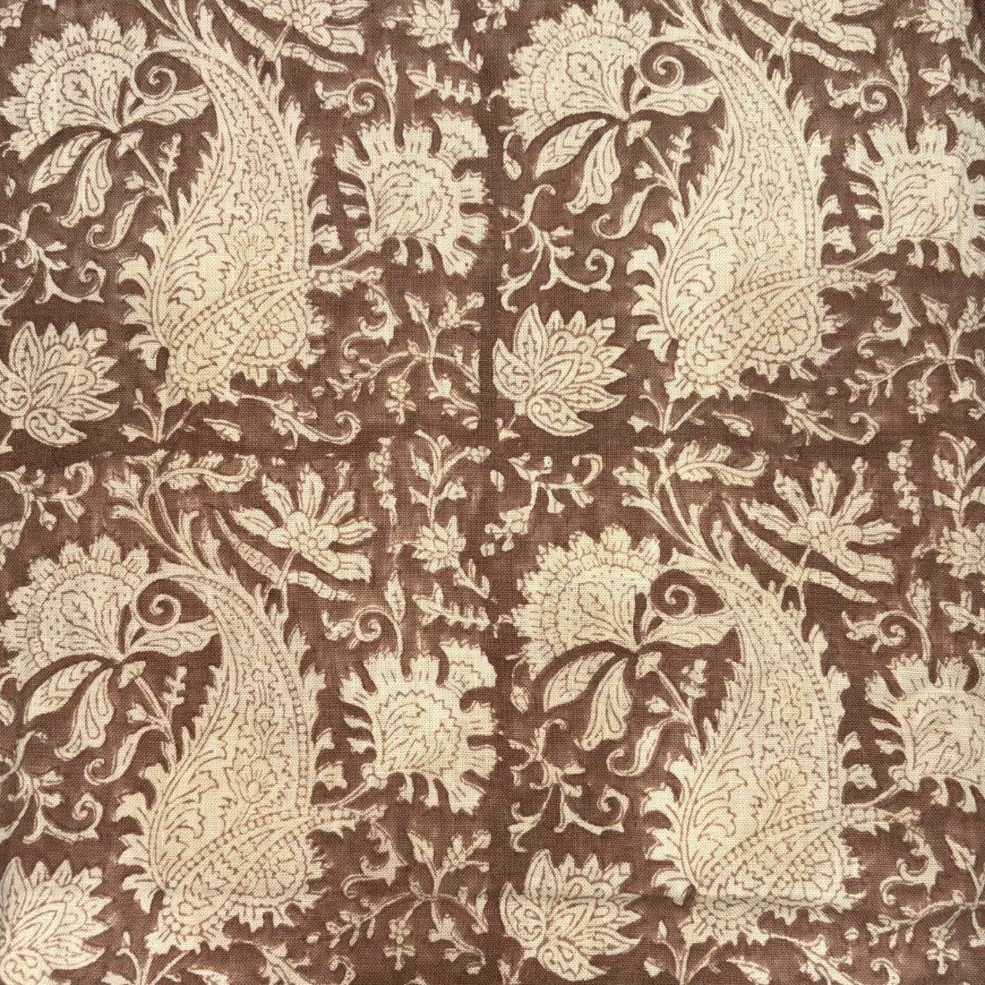 Patterned fabric with beige paisley design on a brown background
