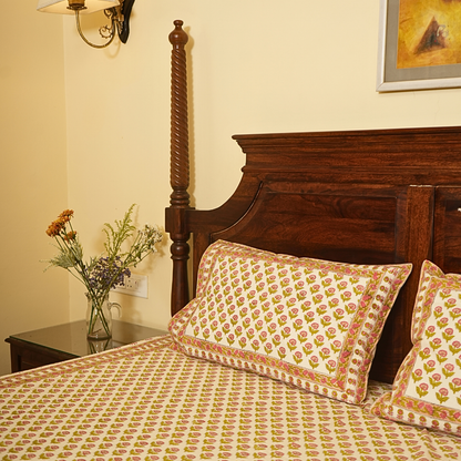 Bedroom with wooden bed and floral bedding, nightstand with flowers, and wall art.