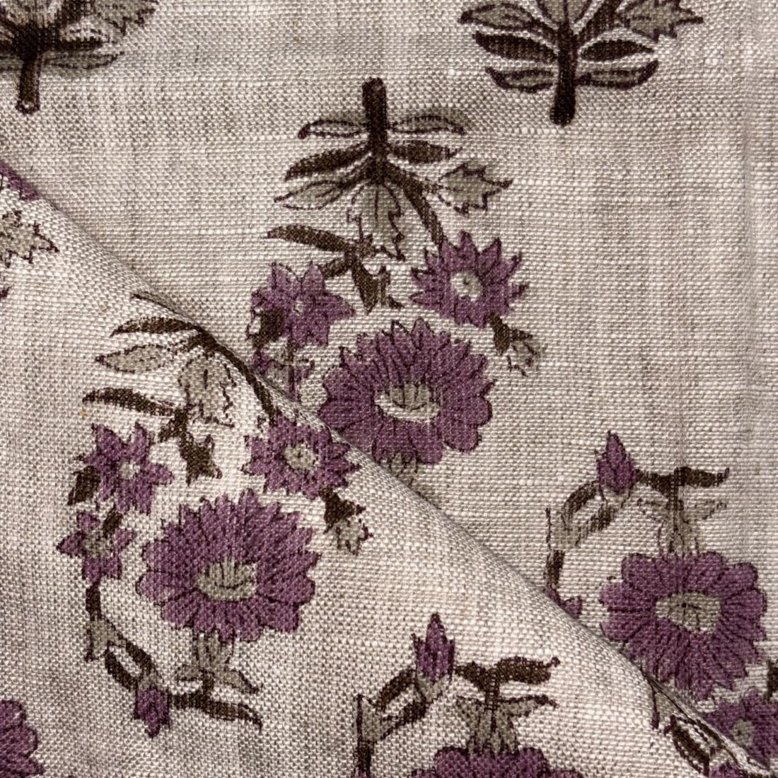 Close-up of floral embroidery on fabric with purple flowers and green leaves.