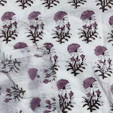 White fabric featuring a repeating block print pattern of purple flowers and dark green leaves.