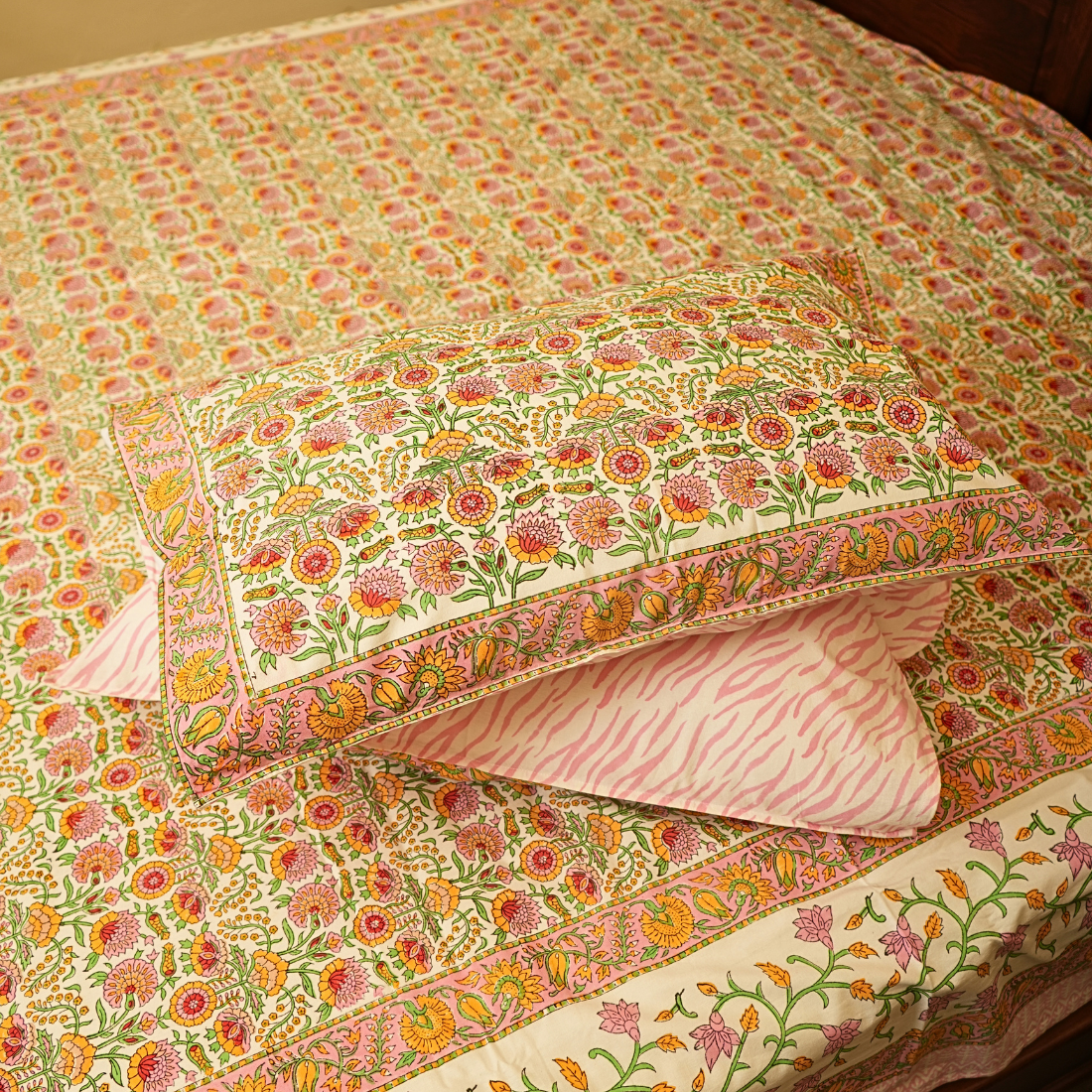 Floral patterned bedspread with matching pillows on a bed.
