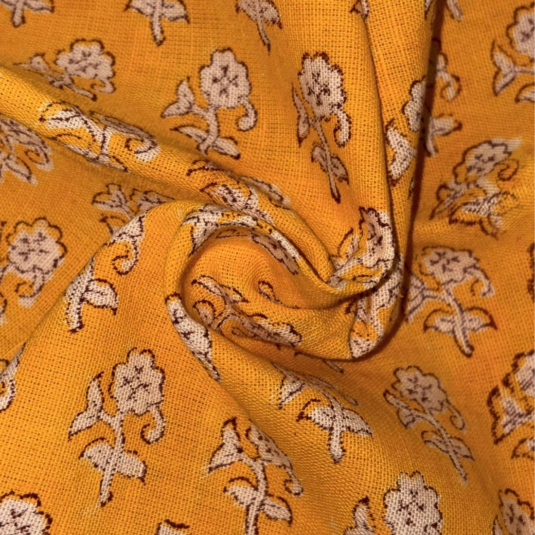 Close-up of yellow fabric with beige floral patterns