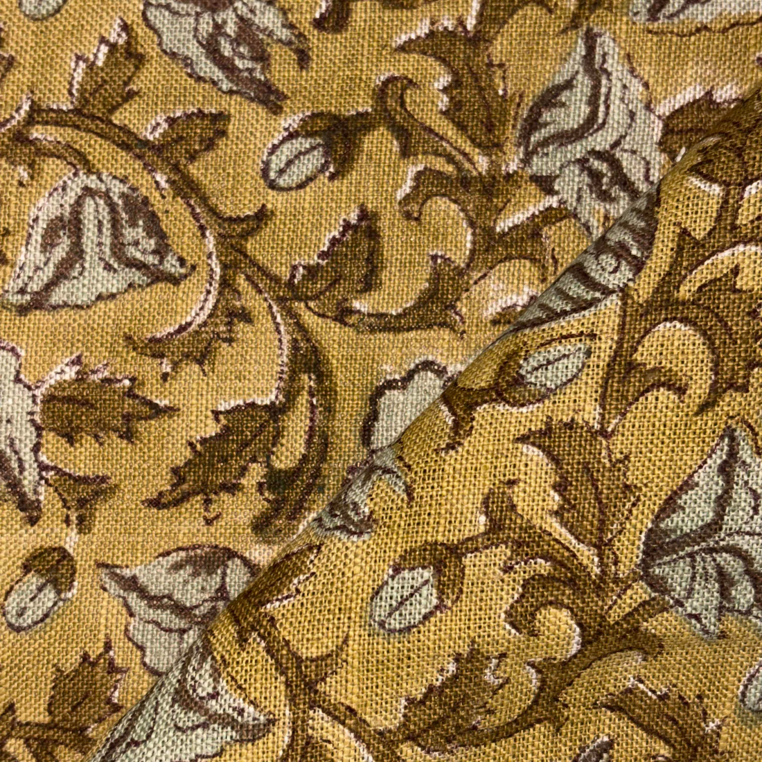 Close-up of a patterned fabric with leaves and vines on a yellow background